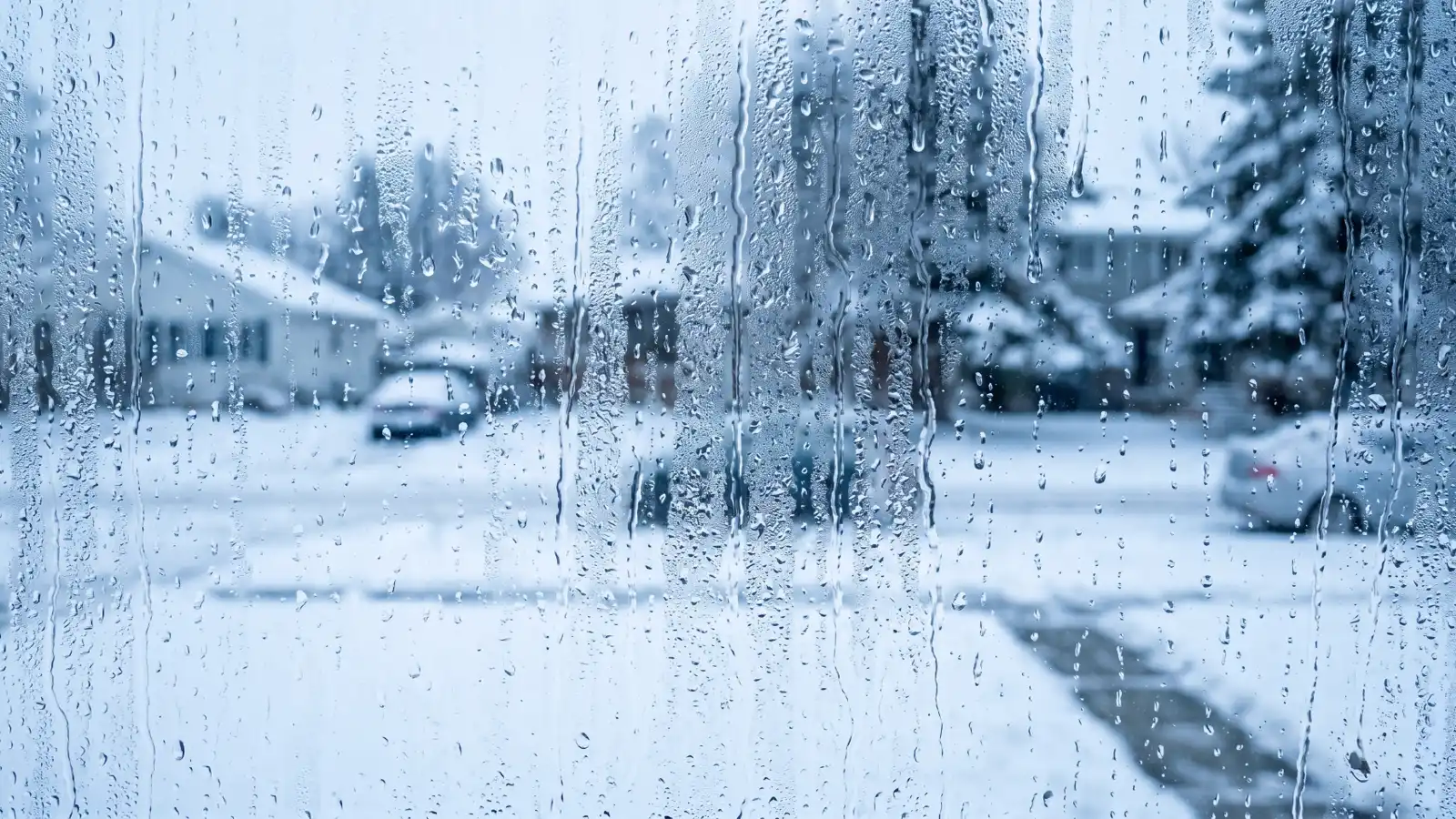 Heavy condensation on a window with a snow-covered street visible outside in winter