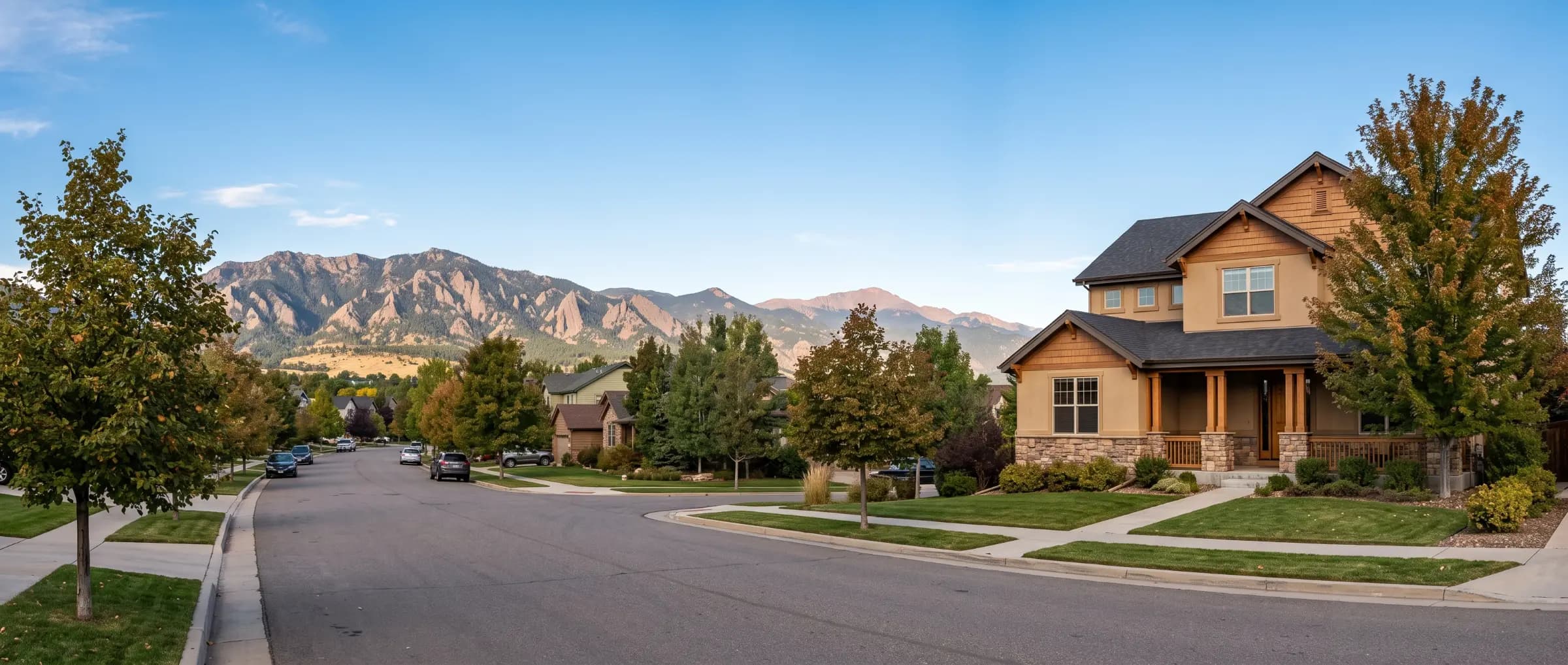 A Denver suburban street with a two story home and the Rocky Mountain foothills in the background