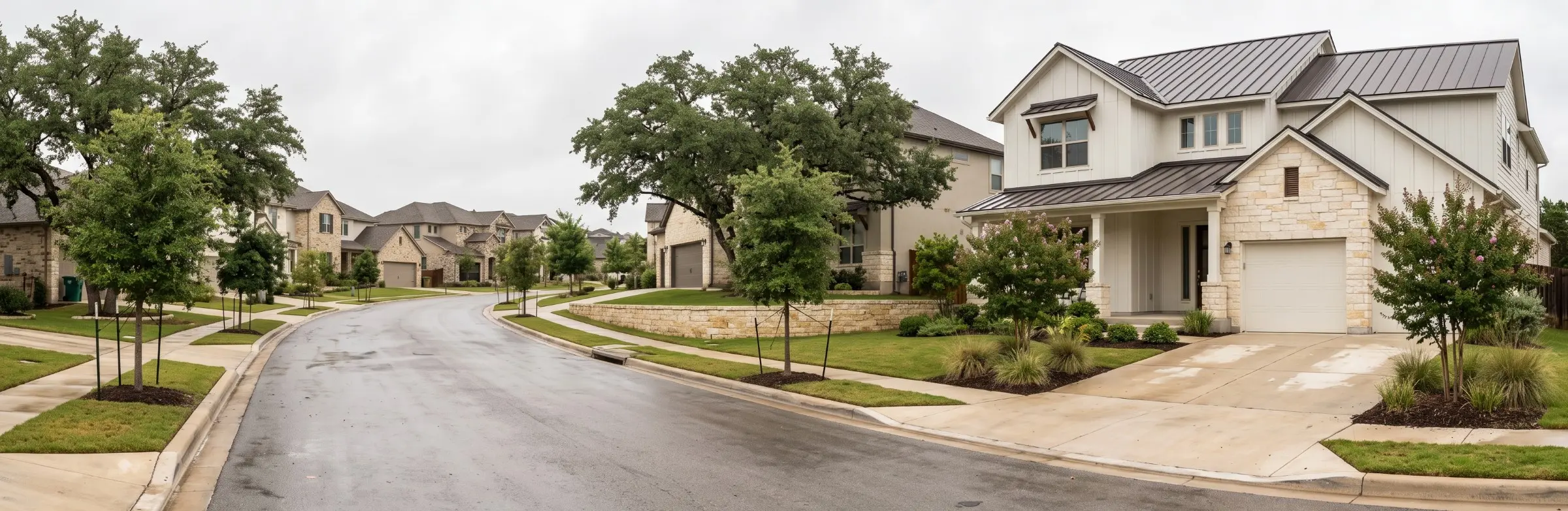Large two-story modern farmhouse style home with limestone accents on a residential street lined with live oaks in Austin, Texas